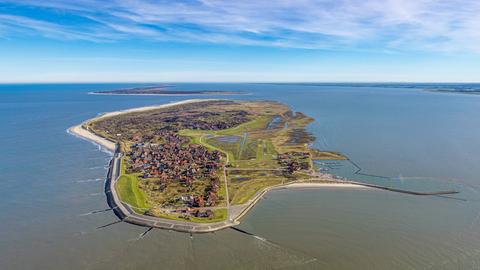 Ein Luftbild zeigt die Insel Baltrum in der Nordsee mit dem Hafen Baltrum, Hafenmole, Fernsicht und blauem Himmel.