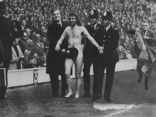 Der Flitzer Michael O´Brien, eskortiert von Polizisten, wird am 1. April 1974 in London im Stadion Twickenham vom Platz geführt.
