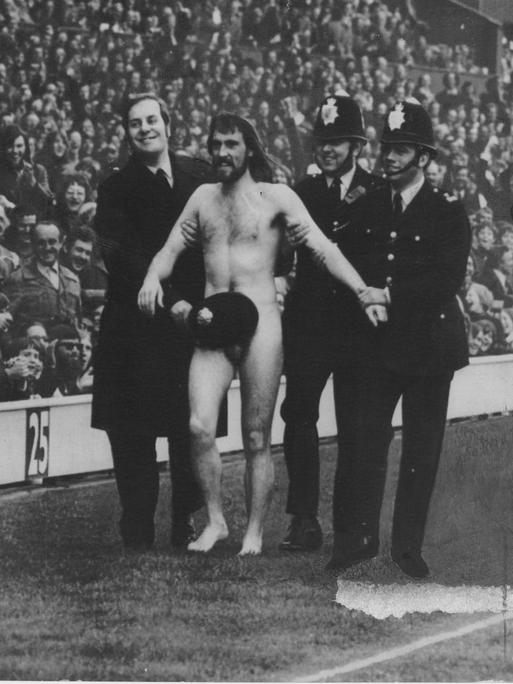Der Flitzer Michael O´Brien, eskortiert von Polizisten, wird am 1. April 1974 in London im Stadion Twickenham vom Platz geführt.
