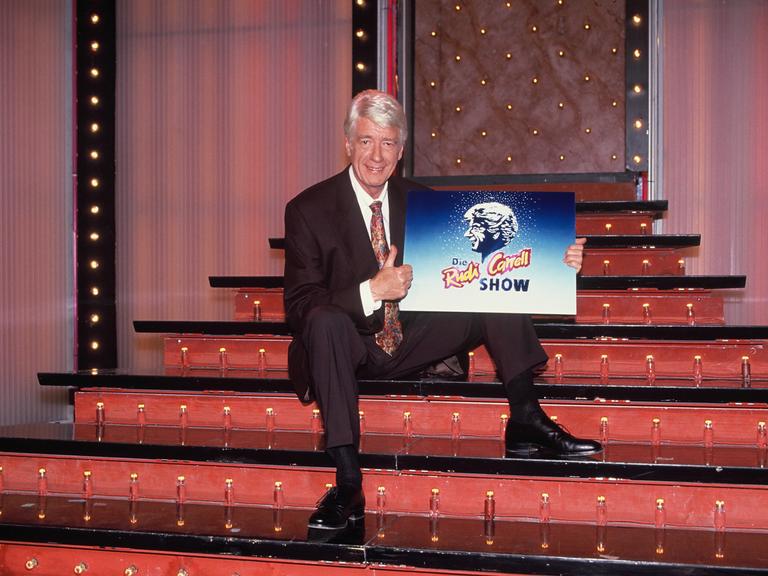 Showmaster und Entertainer Rudi Carrell posiert mit dem Logo der Rudi Carrell Show auf der Showtreppe im Jahre 1992