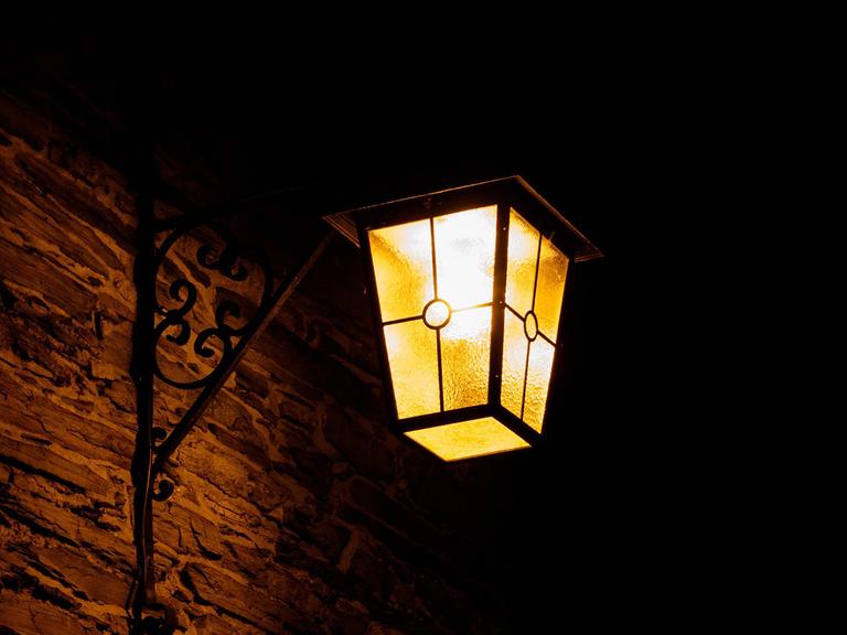 Eine leuchtende Laterne an einer Wand in der Nacht. 