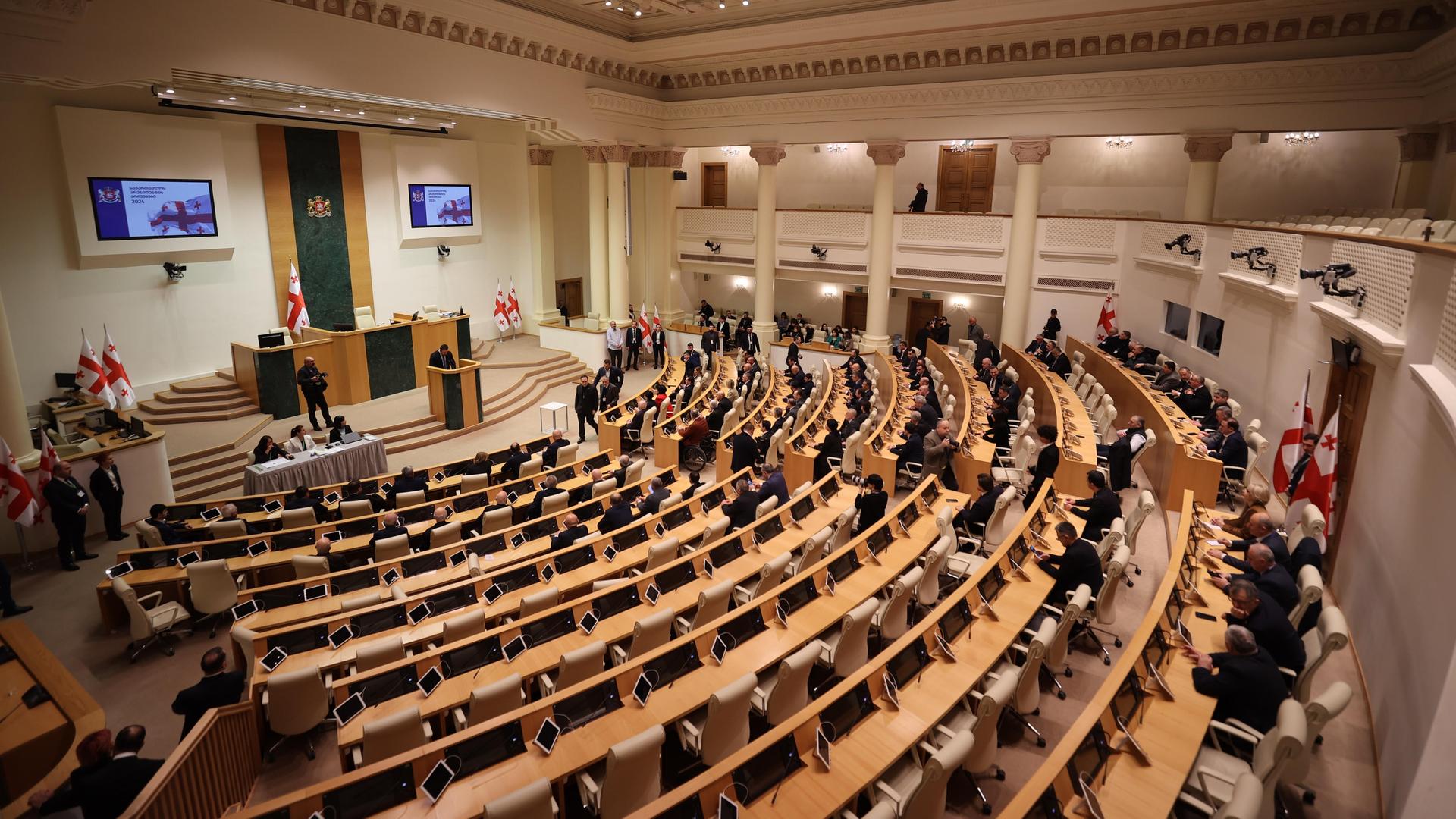 Blick in das georgische Parlament, viele Sitzreihen sind leer.