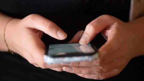 Eine Person tippt auf einem Handy. 