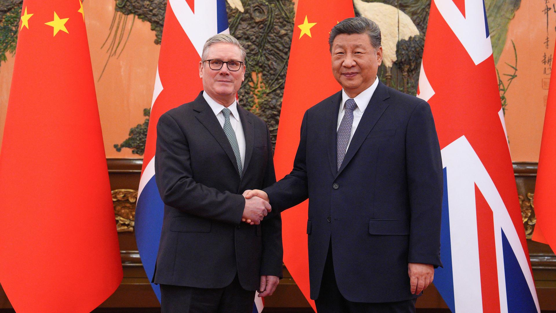 Chinas Präsident Xi Jinping (R) and der britische Premierminister Keir Starmer schütteln sich die Hände. Im Hintergrund sind die Flaggen ihrer beiden Länder zu sehen. Chinas Präsident Xi Jinping (R) and der britische Premierminister Keir Starmer schütteln sich die Hände. Im Hintergrund sind die Flaggen ihrer beiden Länder zu sehen.