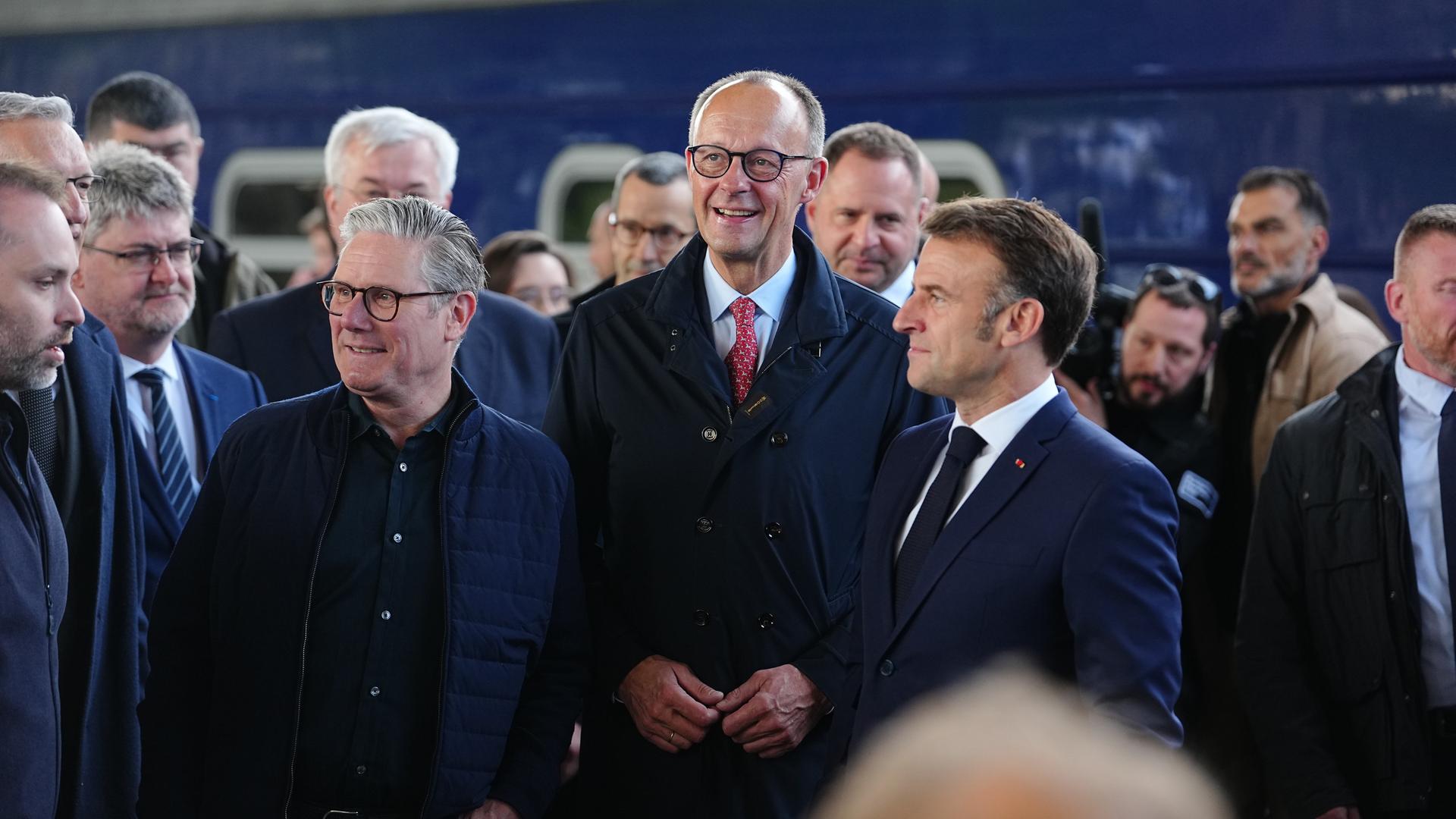Der britische Premierminister Keir Starmer, Bundeskanzler Friedrich Merz und Frankreichs Staatspräsident Emmanuel Macron (v.l.n.r.) stehen in einer Menschenmenge auf dem Bahnsteig. Im Hintergrund ein Zug. Der britische Premierminister Keir Starmer, Bundeskanzler Friedrich Merz und Frankreichs Staatspräsident Emmanuel Macron (v.l.n.r.) stehen in einer Menschenmenge auf dem Bahnsteig. Im Hintergrund ein Zug.