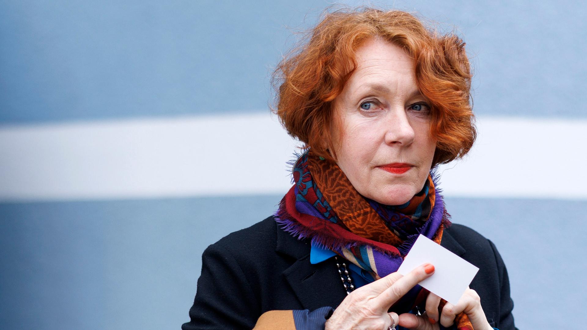 Eine Frau mit roten Haaren hält ein Kärtchen in der Hand.