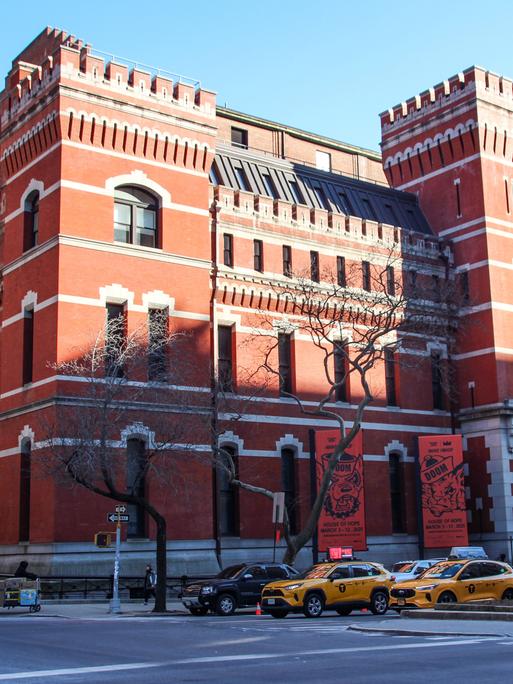 Das wie eine Ritterburg mit Türmen gestaltete Park Avenue Armory Center, davor stehen Autos an einer Kreuzung.
