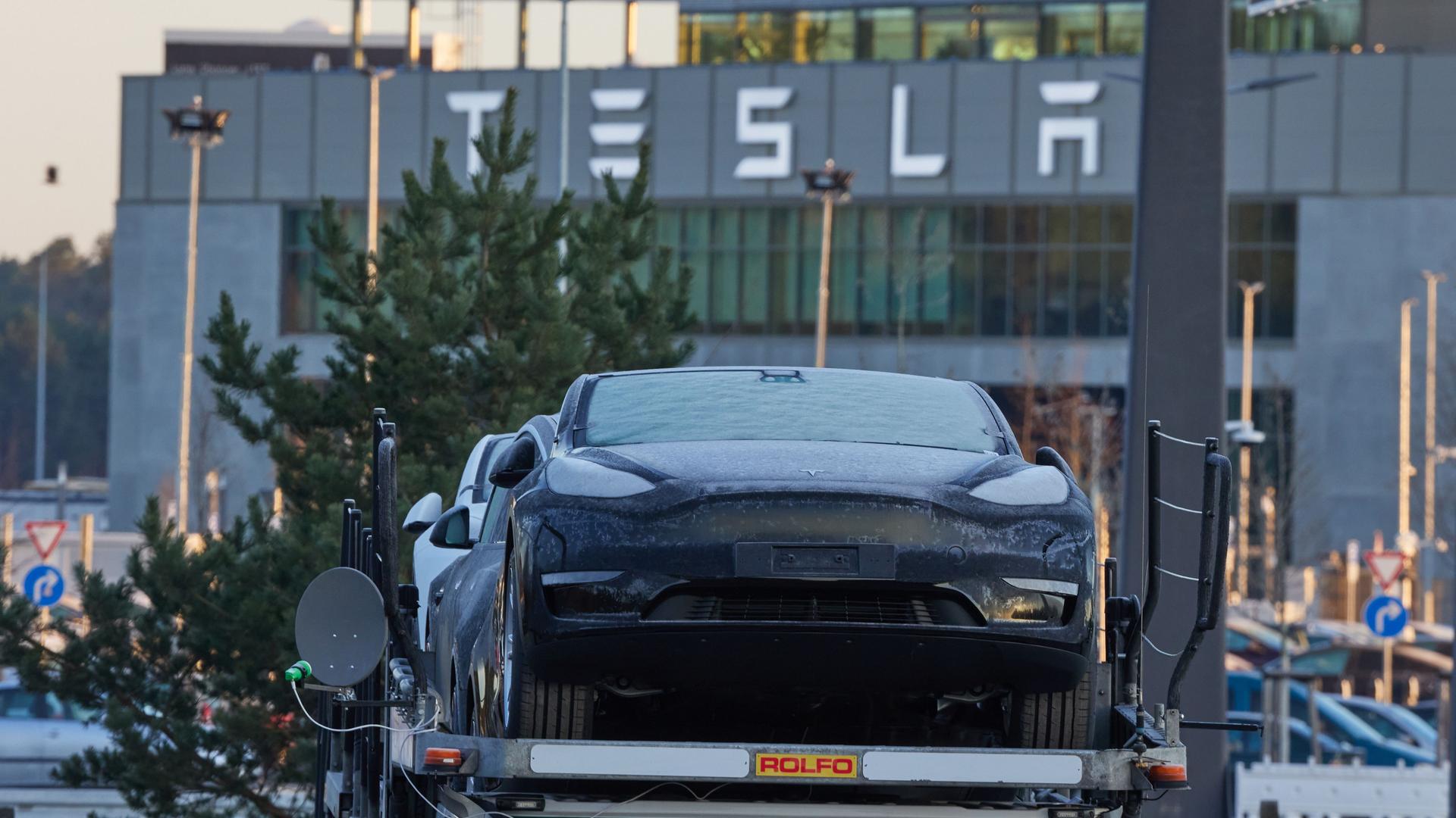 Brandenburg, Grünheide: Ein Tesla-PKW steht am frühen Morgen vor der Tesla-Autofabrik auf einem Transporter.