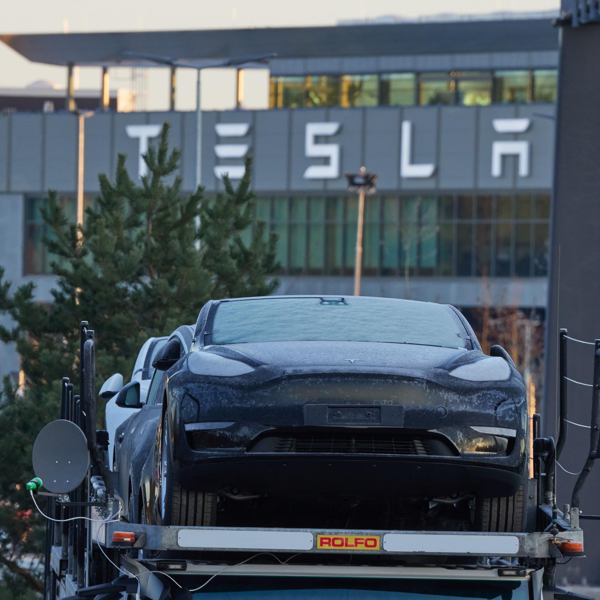 Brandenburg, Grünheide: Ein Tesla-PKW steht am frühen Morgen vor der Tesla-Autofabrik auf einem Transporter.  