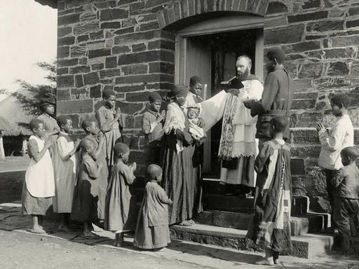 In der Missionsstation Maria Trost des Klosters Mariannhill in Südafrika tauft ein Priester 1912 ein afrikanisches Kind. 