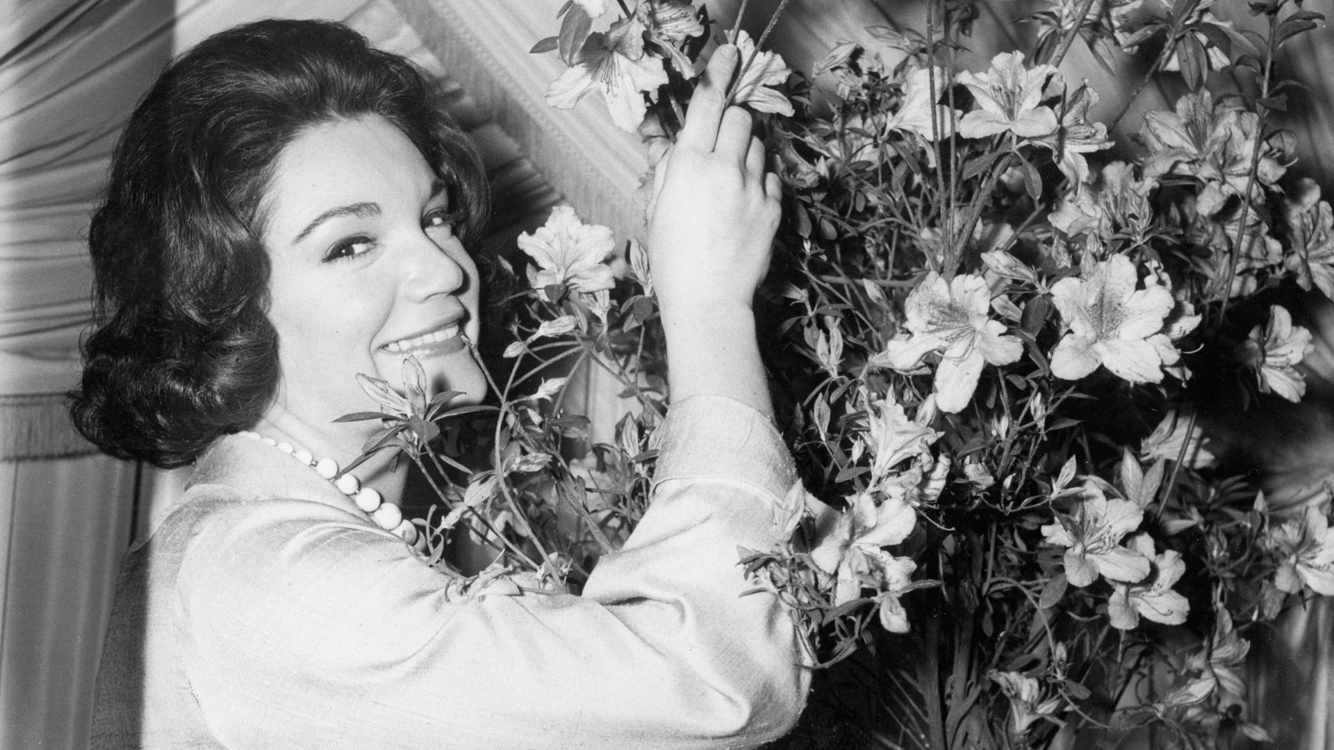 Connie Francis riecht an einem großen Blumenstrauß. Das Foto ist schwarz-weiß.