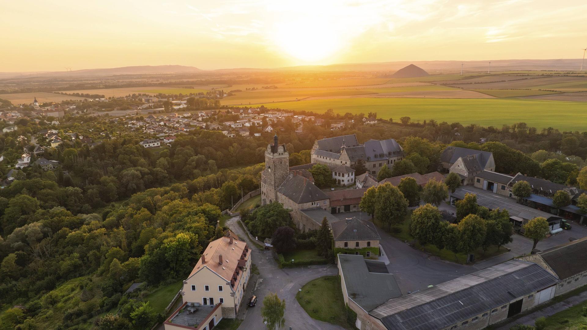 Luftaufnahme von Allstedt mit der Burg Allstedt im Vordergrund. Im Hintergrund geht die Sonne unter. 