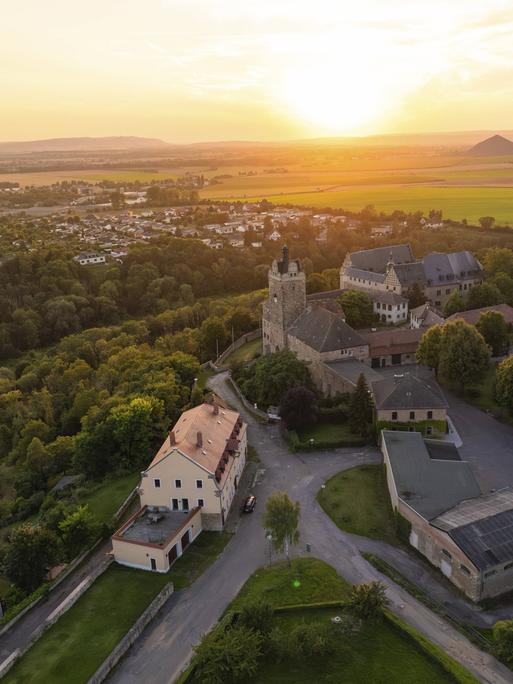 Luftaufnahme von Allstedt mit der Burg Allstedt im Vordergrund. Im Hintergrund geht die Sonne unter. 