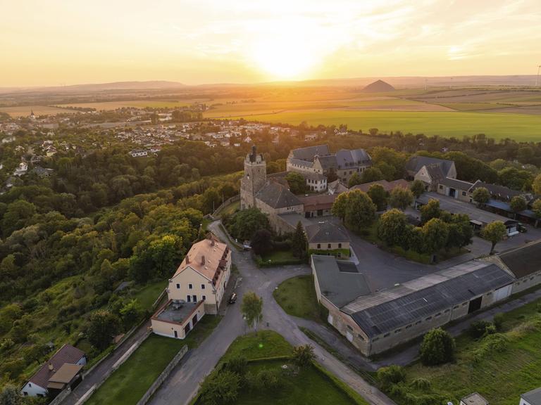 Luftaufnahme von Allstedt mit der Burg Allstedt im Vordergrund. Im Hintergrund geht die Sonne unter. 