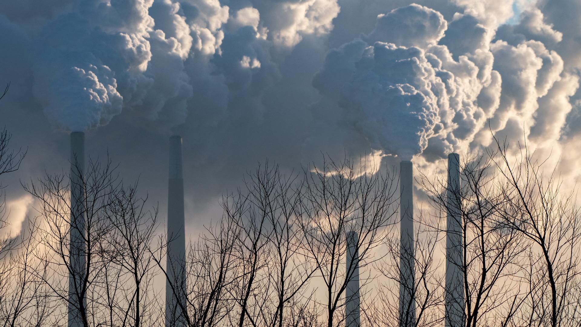 Rauchwolken steigen aus riesigen Industrieschornsteinen auf.