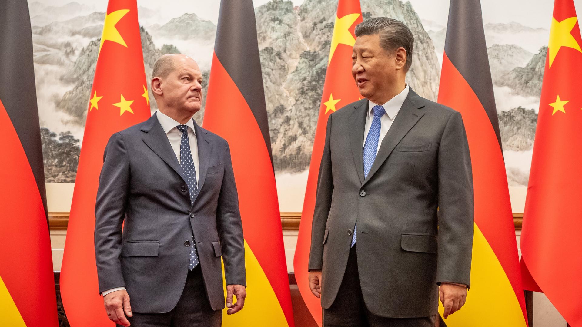 China, Peking: Bundeskanzler Olaf Scholz wird von Xi Jinping, Staatspräsident von China, im Staatsgästehaus empfangen. Hinter ihnen die Nationalflaggen Deutschlands und Chinas.
