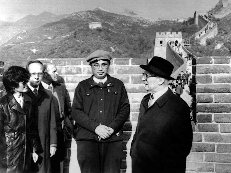 Chinesische Männer udn ein Europäer mit Hut stehen auf der Großen Mauer in China.