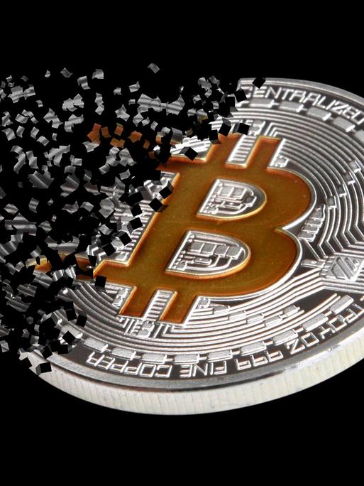 Ein physischer Bitcoin, der zerfällt vor schwarzem Hintergrund.