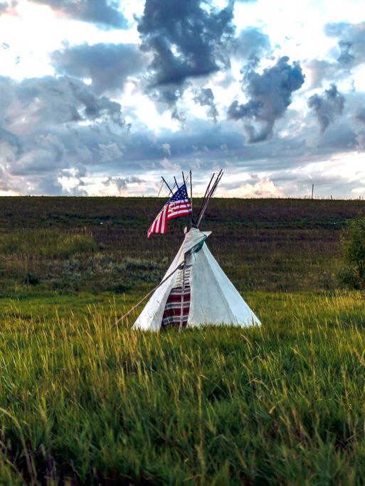 Ein Tipi steht mit einer amerikanische Flagge auf einem Grasfeld in der Nähe des Standing Rock Sioux Reservats in North Dakota.
