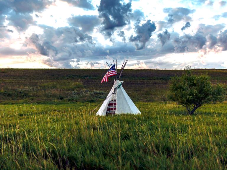 Ein Tipi steht mit einer amerikanische Flagge auf einem Grasfeld in der Nähe des Standing Rock Sioux Reservats in North Dakota.