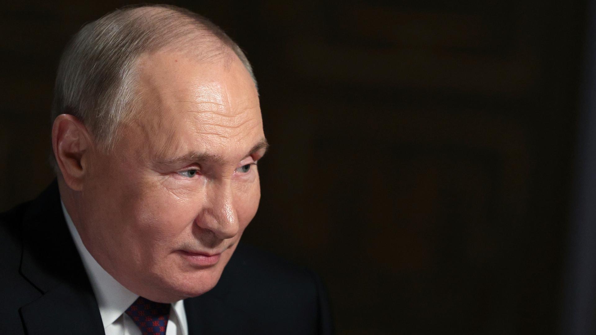 Russlands Präsident Putin im Porträt vor schwarzem Hintergrund.