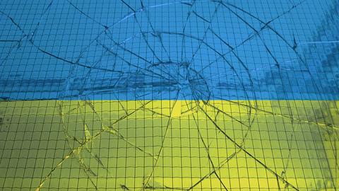 Eine ukrainische Flagge hinter einer zerbrochenen Glasscheibe