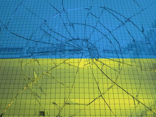 Eine ukrainische Flagge hinter einer zerbrochenen Glasscheibe