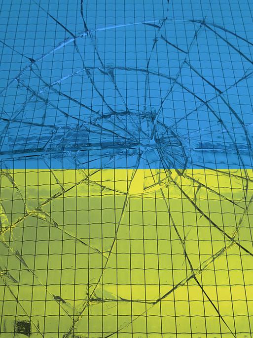 Eine ukrainische Flagge hinter einer zerbrochenen Glasscheibe