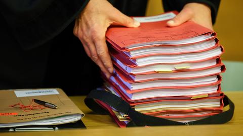 Ein Staatsanwalt legt vor Prozessbeginn einen Stapel Akten auf seinen Tisch.
