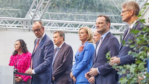 Friedrich Merz steht an einem Redepult und spricht in Mikrofone. Neben ihm ist eine Reihe von Unions-Politikerinnen und -Politikern zu sehen.