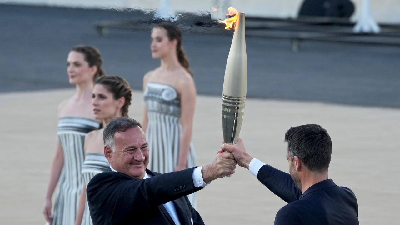 Der Präsident des griechischen Olympischen Komitees, Spyros Kapralos, bei der Übergabe des Olympischen Feuers an den Präsidenten des französischen Organisationskomitees, Tony Estanguet.
