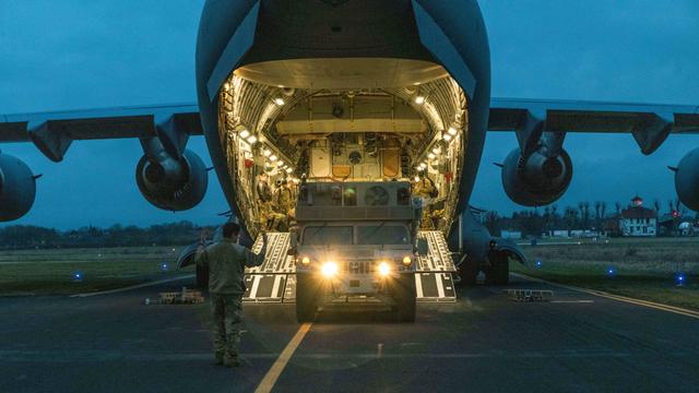 Zu sehen ist eine US-Militärtransportmaschine auf dem Flugfeld in Wiesbaden. Ein Jeep wird ausgeladen. Im Vordergrund steht ein Soldat.