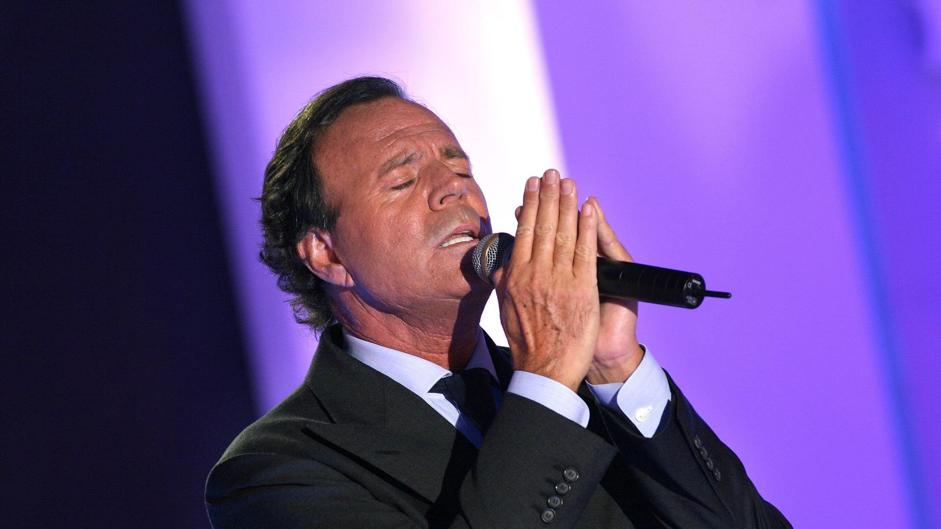Julio Iglesias singt mit geschlossenen Augen in ein Mikrofon.