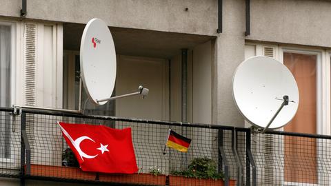 Satellitenschüsseln auf einem Balkon mit deutscher und türkischer Flagge.