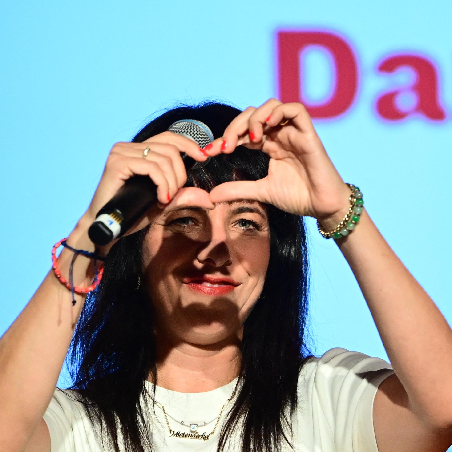 Linken-Spitzenkandidatin Elif Eralp spricht auf einer Wahlparty in Berlin und formt mit ihren Händen ein Herz.