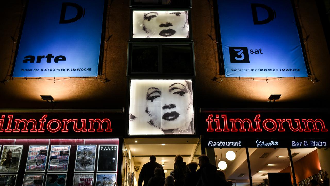 Menschen betreten im Rahmen der Duisburger Filmwoche das Kino "Filmforum".