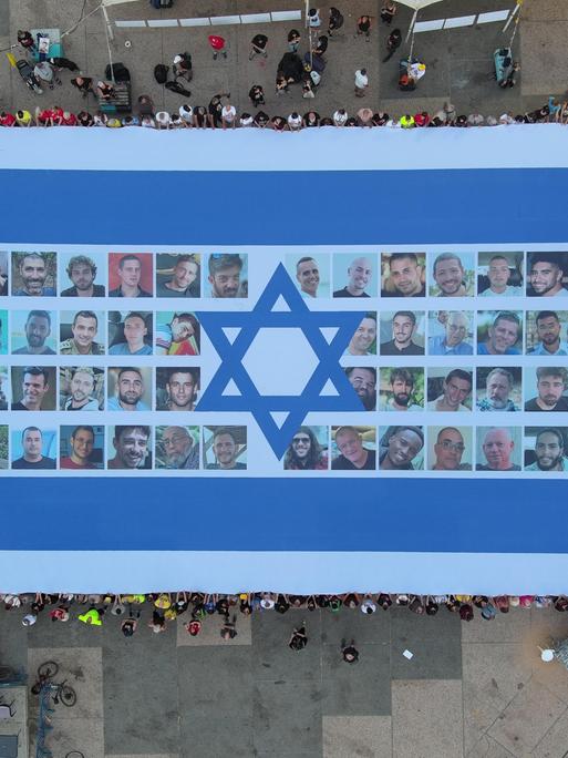 Eine riesige Fahne mit Bildern der nach Gaza verschleppten israelischen Geiseln von oben fotografiert