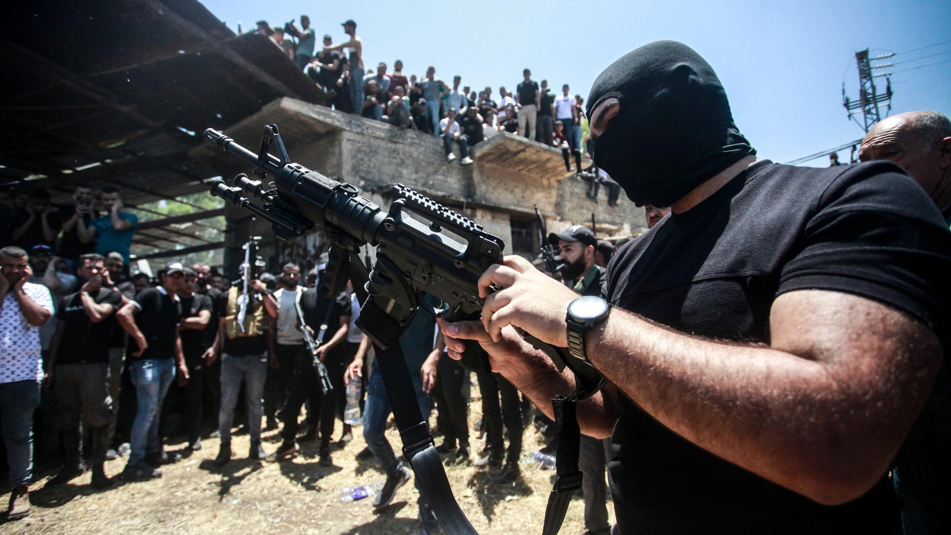 Ein bewaffneter Palästinenser schießt bei einer Beerdigung in die Luft.