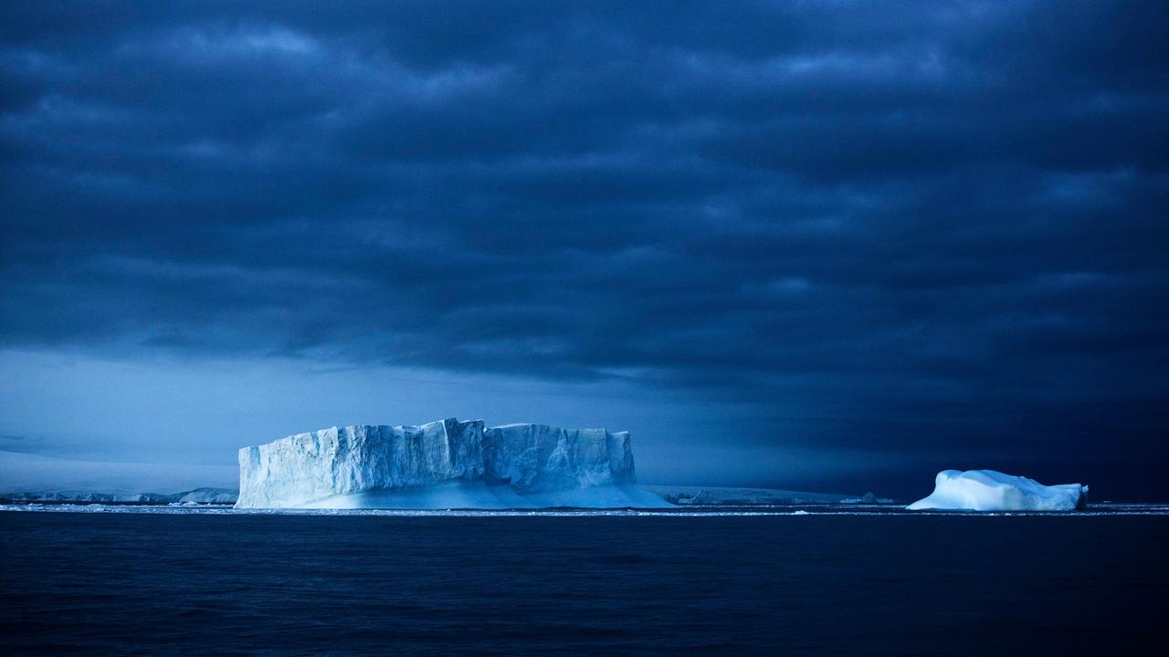 Eisberge im Meer vor einem dunklen Himmel Eisberge im Meer vor einem dunklen Himmel