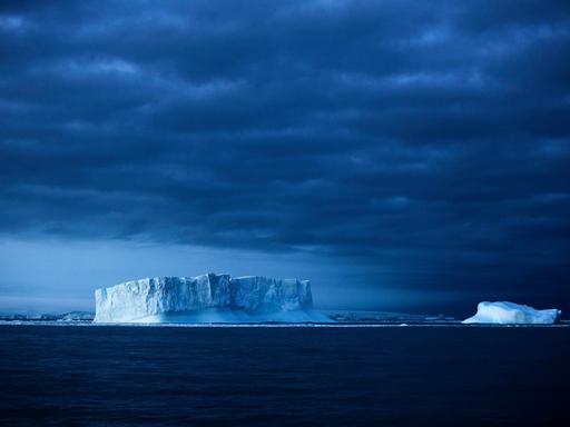 Eisberge im Meer vor einem dunklen Himmel Eisberge im Meer vor einem dunklen Himmel