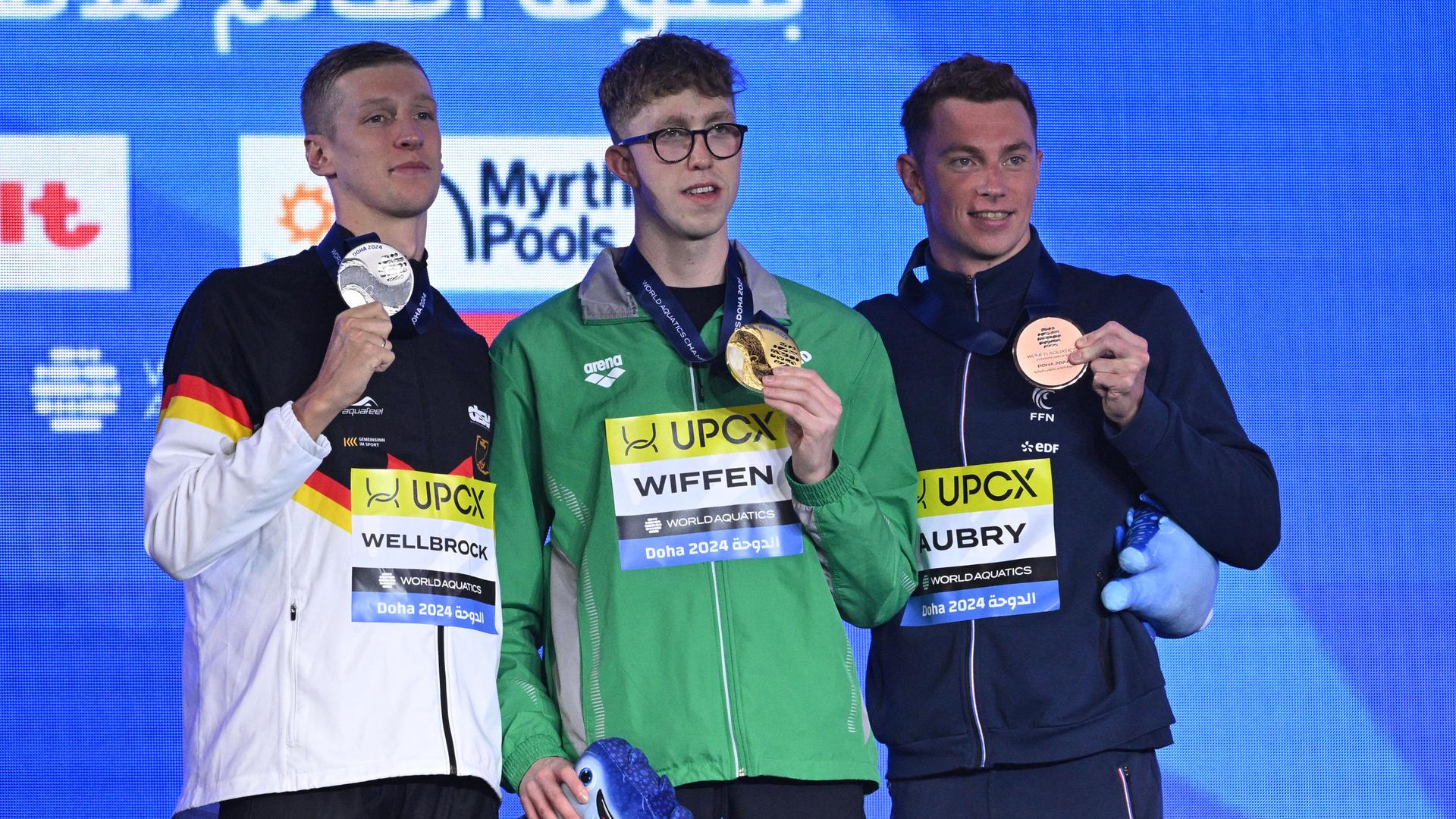 Drei Schwimmer stehen während der Siegerehrung mit Gold, Silber und Bronze auf dem Podest.