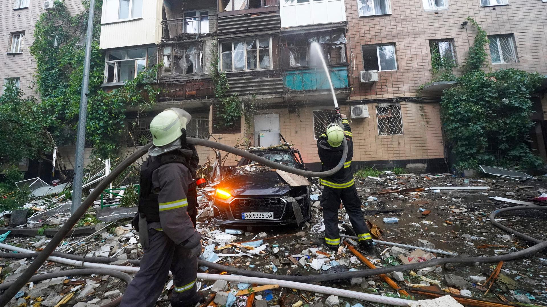Feuerwehrleute löschen von außen einen Brand in einem mehrstöckigen Wohnhaus. Feuerwehrleute löschen von außen einen Brand in einem mehrstöckigen Wohnhaus.