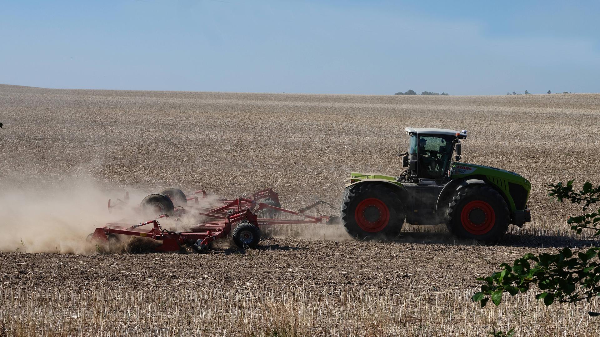 Ein Bauer in der Uckermark fährt mit einer Landmaschine über ausgetrocknete staubige Felder.