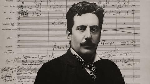 Wir sehen eine Collage: Auf ihr zu sehen ist der Komponist Giacomo Puccini vor einem dicht beschrifteten Notenblatt.