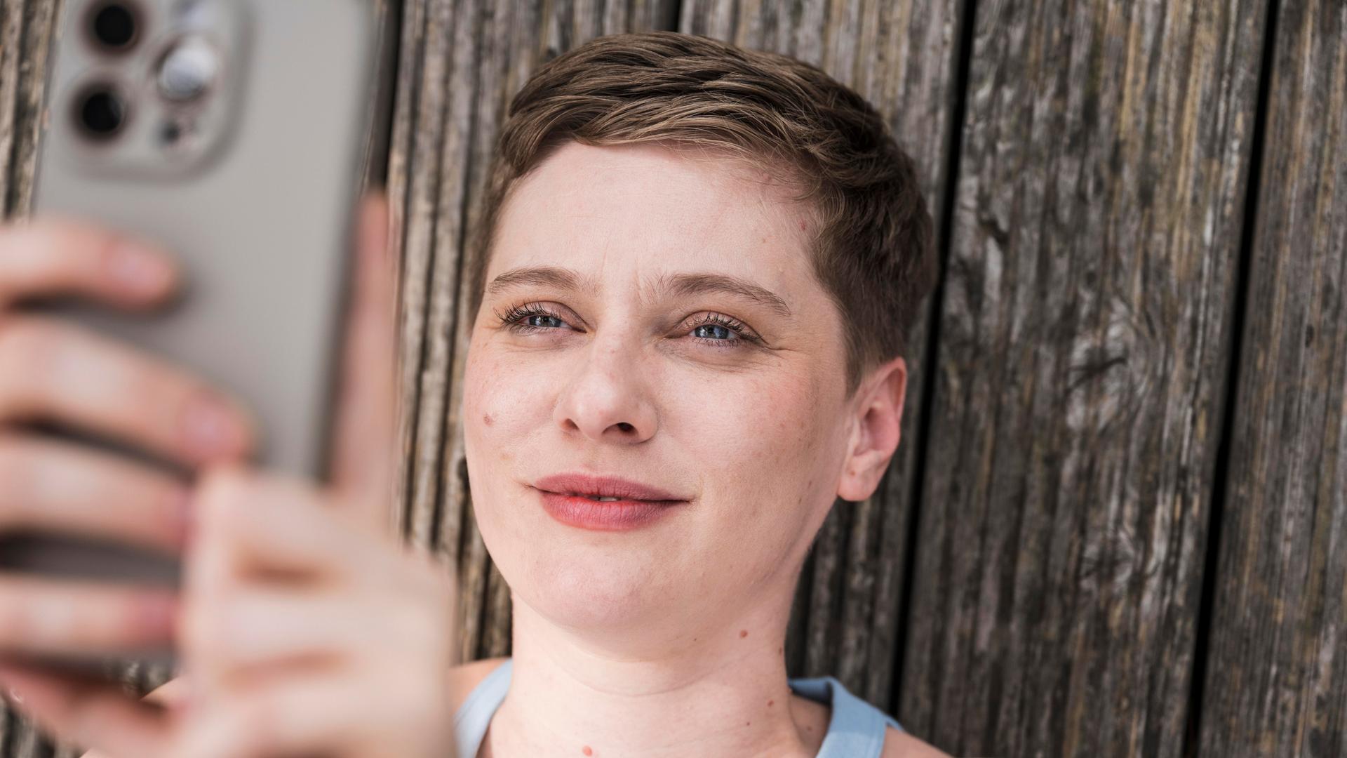 Eine junge Frau blickt lächelnd in ihr Smartphone. Eine junge Frau blickt lächelnd in ihr Smartphone.