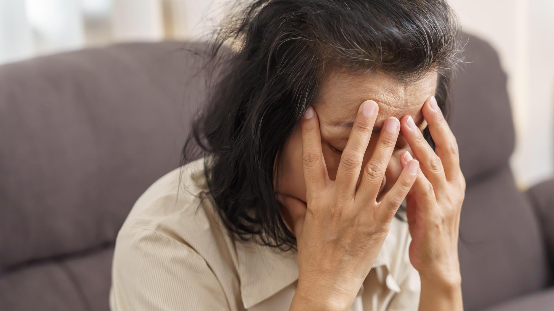 Eine Frau hält ihren Kopf mit geschlossenen Augen in den Händen Eine Frau hält ihren Kopf mit geschlossenen Augen in den Händen