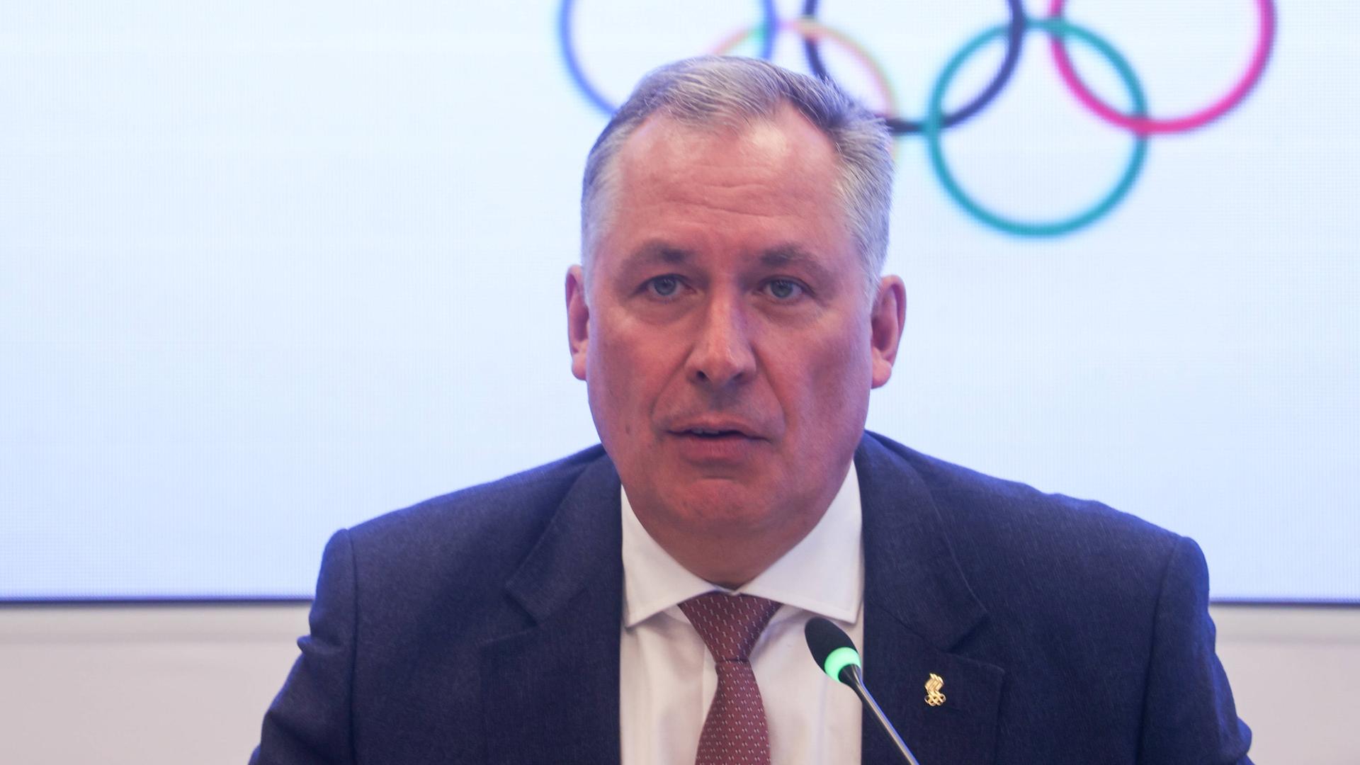 Stanislaw Posdnjakow schaut in die Kamera, hinter ihm sind die Olympischen Ringe zu sehen.