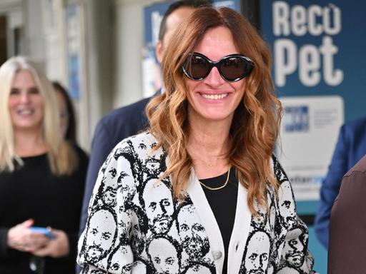 Die US-Schauspielerin Julia Roberts trägt eine große Sonnenbrille und eine helle Jacke mit einem Männerkopf-Muster, als sie am Flughafen in Venedig ankommt.