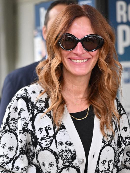 Die US-Schauspielerin Julia Roberts trägt eine große Sonnenbrille und eine helle Jacke mit einem Männerkopf-Muster, als sie am Flughafen in Venedig ankommt.