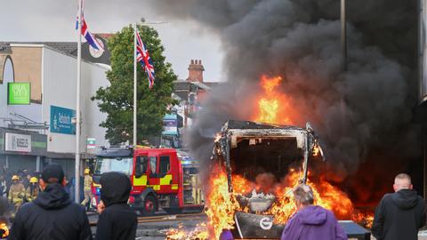 In Belfast kommt es während einer Demonstration zu Ausschreitungen. Fahrzeuge stehen in Flammen. 